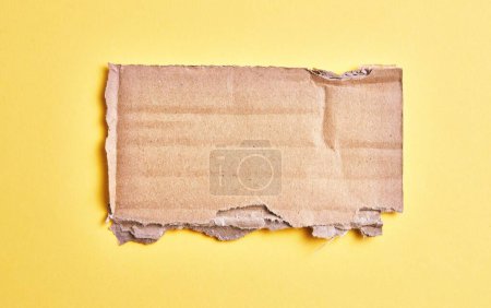Téléchargez les photos : Un morceau de carton déchiré sur fond jaune isolé - en image libre de droit