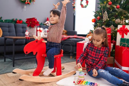 Photo for Adorable boy and girl playing with reindeer rocking and toy celebrating christmas at home - Royalty Free Image