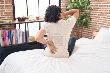 Photo for Young latin man suffering for back injury sitting on bed at bedroom - Royalty Free Image