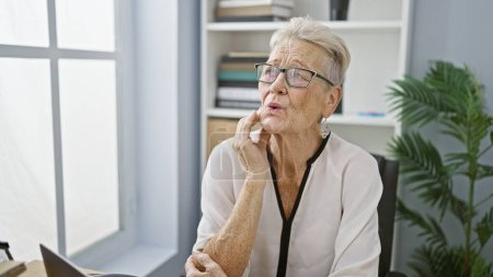 Téléchargez les photos : Femme âgée aux cheveux gris qui travaille au bureau et qui souffre de maux de dents grève pendant la journée de travail - en image libre de droit
