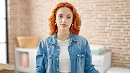 Photo for Young redhead woman standing with relaxed expression at laundry room - Royalty Free Image
