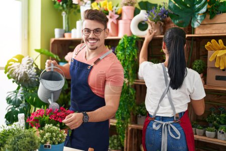 Téléchargez les photos : Fleuristes homme et femme arrosage usine travaillant à la boutique de fleurs - en image libre de droit
