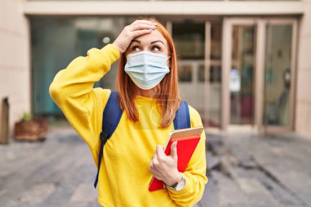 Photo for Young woman wearing safety mask and student backpack holding books stressed and frustrated with hand on head, surprised and angry face - Royalty Free Image
