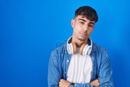 Photo for Young hispanic man standing over blue background looking sleepy and tired, exhausted for fatigue and hangover, lazy eyes in the morning. - Royalty Free Image