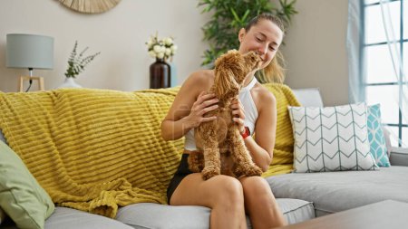 Photo for Young caucasian woman with dog playing sitting on the sofa at home - Royalty Free Image