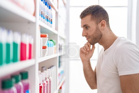 Photo for Young caucasian man customer looking shelving at pharmacy - Royalty Free Image