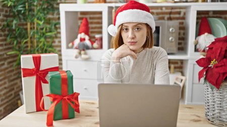 Photo for Young blonde woman using laptop celebrating christmas at dinning room - Royalty Free Image
