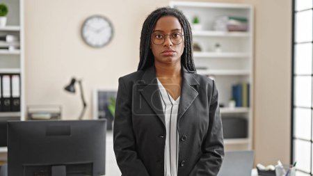 Téléchargez les photos : Femme afro-américaine ouvrière avec un visage sérieux au bureau - en image libre de droit