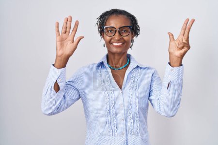 Téléchargez les photos : Femme africaine avec dreadlocks debout sur fond blanc portant des lunettes montrant et pointant vers le haut avec les doigts numéro neuf tout en souriant confiant et heureux. - en image libre de droit