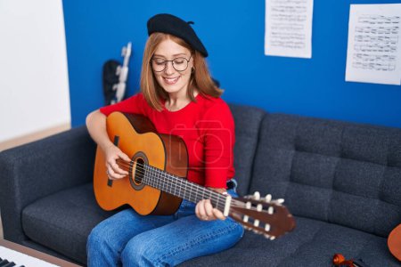 Photo for Young redhead woman musician smiling confident playing classical guitar at music studio - Royalty Free Image