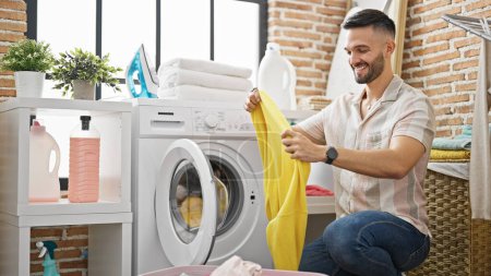 Photo for Young hispanic man smiling confident washing clothes at laundry room - Royalty Free Image