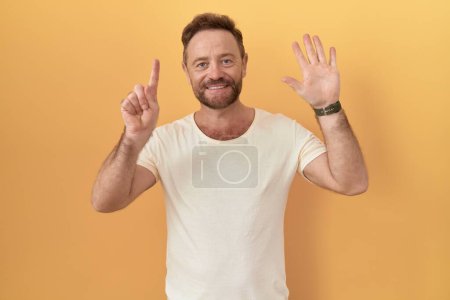 Téléchargez les photos : Homme d'âge moyen avec barbe debout sur fond jaune montrant et pointant vers le haut avec les doigts numéro six tout en souriant confiant et heureux. - en image libre de droit