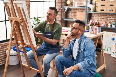 Téléchargez les photos : Deux artistes hommes dessinent avec une expression détendue au studio d'art - en image libre de droit