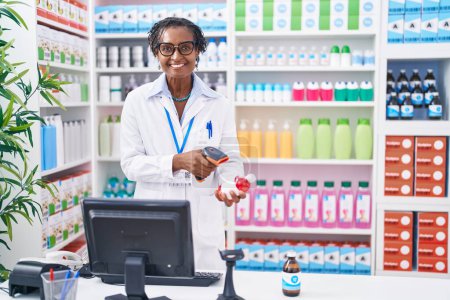 Foto de Mujer afroamericana de mediana edad que escanea la botella de las píldoras del farmacéutico en farmacia - Imagen libre de derechos