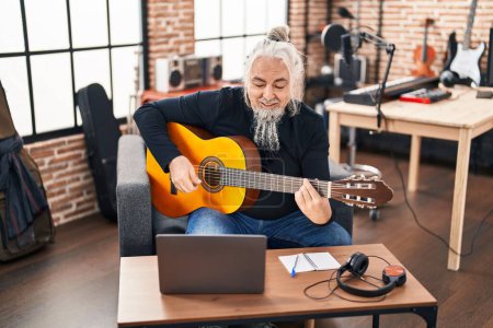 Foto de Hombre músico de pelo gris de mediana edad que tiene clase de guitarra clásica en línea en el estudio de música - Imagen libre de derechos