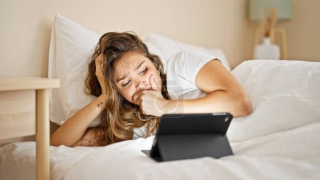Téléchargez les photos : Jeune belle femme hispanique regardant un film d'horreur sur le pavé tactile couché sur le lit dans la chambre - en image libre de droit