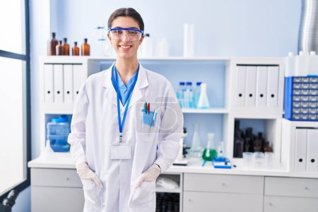 Foto de Young beautiful hispanic woman scientist smiling confident standing at laboratory - Imagen libre de derechos