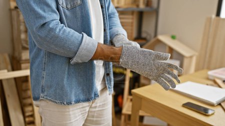 Téléchargez les photos : Mains astucieuses d'un homme hispanique, un menuisier portant des gants plongé dans la menuiserie dans un atelier de menuiserie professionnelle - en image libre de droit