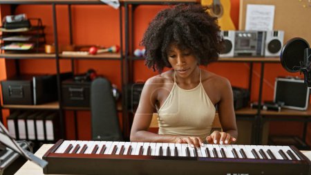 Foto de African american woman musician playing piano at music studio - Imagen libre de derechos