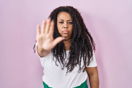 Photo for Plus size hispanic woman standing over pink background doing stop sing with palm of the hand. warning expression with negative and serious gesture on the face. - Royalty Free Image
