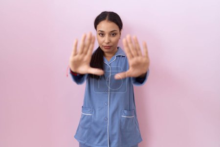 Foto de Mujer árabe joven usando pijama azul haciendo marco usando manos palmas y dedos, perspectiva de la cámara - Imagen libre de derechos
