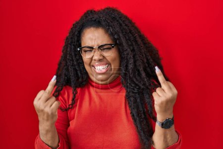 Téléchargez les photos : Plus size hispanic woman standing over red background showing middle finger doing fuck you bad expression, provocation and rude attitude. screaming excited - en image libre de droit