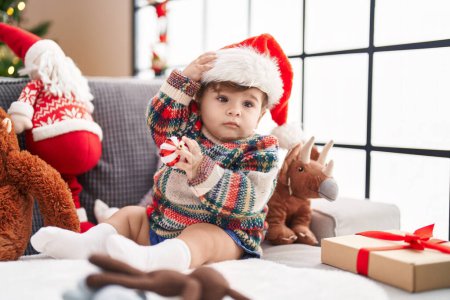 Téléchargez les photos : Adorable bambin hispanique portant un chapeau de Noël tenant le ballon à la maison - en image libre de droit