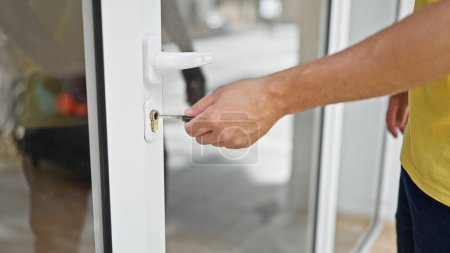 Foto de Joven hispano cerrando la puerta con llave en casa - Imagen libre de derechos