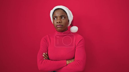 Photo for African american woman standing upset wearing christmas hat over isolated red background - Royalty Free Image