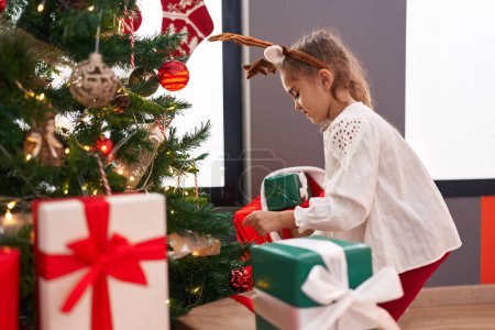 Foto de Adorable chica hispana sonriendo confiada decorando el árbol de Navidad en casa - Imagen libre de derechos