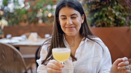 Téléchargez les photos : Jeune belle femme hispanique buvant un cocktail tropical sur la terrasse du bar - en image libre de droit