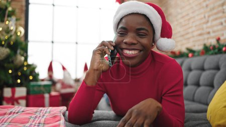 Photo for African american woman talking on smartphone celebrating christmas at home - Royalty Free Image