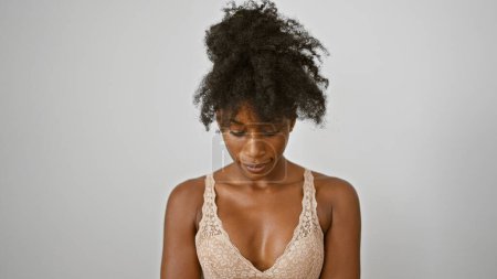 Téléchargez les photos : Femme afro-américaine portant de la lingerie regardant vers le bas sur fond blanc isolé - en image libre de droit