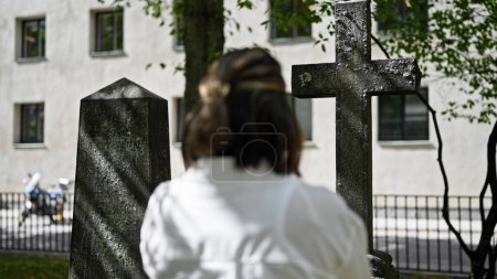 Téléchargez les photos : Belle jeune femme hispanique priant et pleurant par pierre tombale au cimetière - en image libre de droit