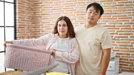 Photo for Man and woman couple holding basket with clothes at laundry room - Royalty Free Image