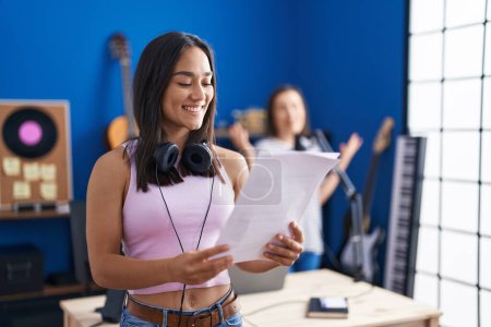 Photo for Two women musicians smiling confident singing song at music studio - Royalty Free Image