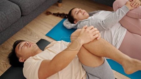 Photo for Man and woman couple lying on yoga mat stretching legs at home - Royalty Free Image