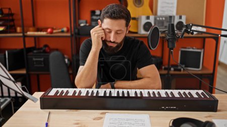 Foto de Joven músico hispano tocando el piano estresado en estudio de música - Imagen libre de derechos
