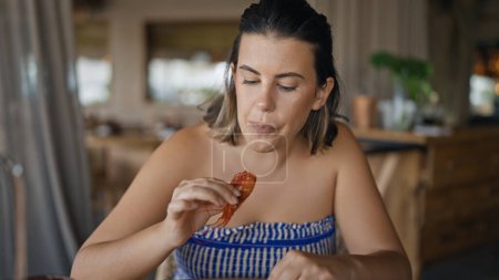Téléchargez les photos : Jeune femme hispanique mangeant des crevettes têtes au restaurant - en image libre de droit