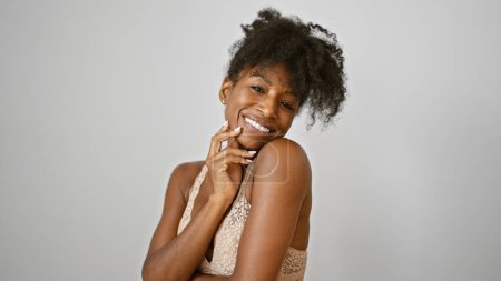 Téléchargez les photos : Femme afro-américaine portant lingerie toucher visage souriant sur fond blanc isolé - en image libre de droit