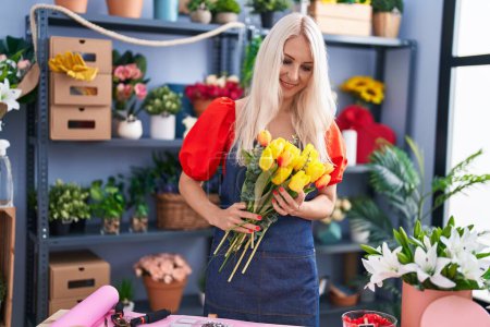 Photo for Young blonde woman florist holding bouquet of flowers at florist store - Royalty Free Image
