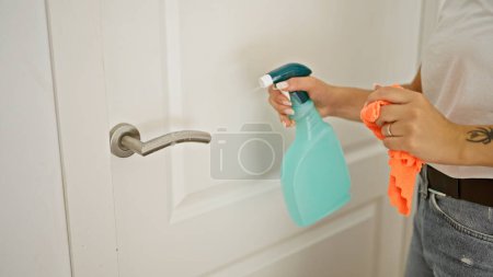 Photo for Young woman cleaning knob door at home - Royalty Free Image