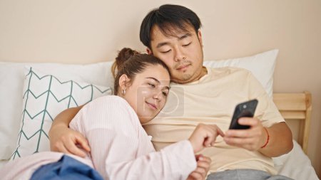 Téléchargez les photos : Homme et femme couple couché sur le lit en utilisant smartphone dans la chambre - en image libre de droit