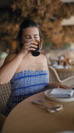 Photo for Young hispanic woman drinking a glass of water at the restaurant - Royalty Free Image