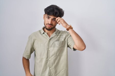 Téléchargez les photos : Homme arabe avec la barbe debout sur fond blanc pointant malheureux à boutons sur le front, infection laide de la tête noire. acné et problème de peau - en image libre de droit