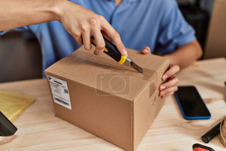 Téléchargez les photos : Jeune homme blond commerce électronique travailleur d'affaires déballage boîte en carton au bureau - en image libre de droit