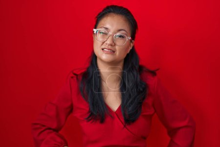 Téléchargez les photos : Asiatique jeune femme debout sur fond rouge clin d'oeil en regardant la caméra avec une expression sexy, gai et heureux visage. - en image libre de droit