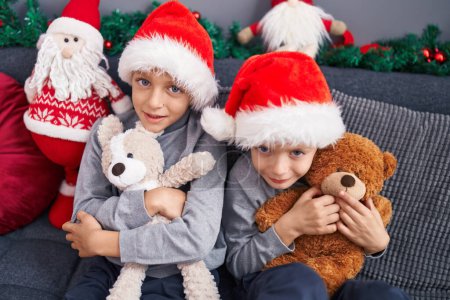 Photo for Adorable boys hugging teddy bear celebrating christmas at home - Royalty Free Image