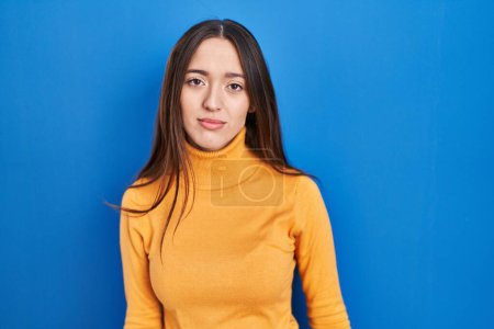 Téléchargez les photos : Young brunette woman standing over blue background looking sleepy and tired, exhausted for fatigue and hangover, lazy eyes in the morning. - en image libre de droit