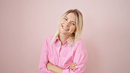 Téléchargez les photos : Young blonde woman smiling confident standing with arms crossed gesture over isolated pink background - en image libre de droit